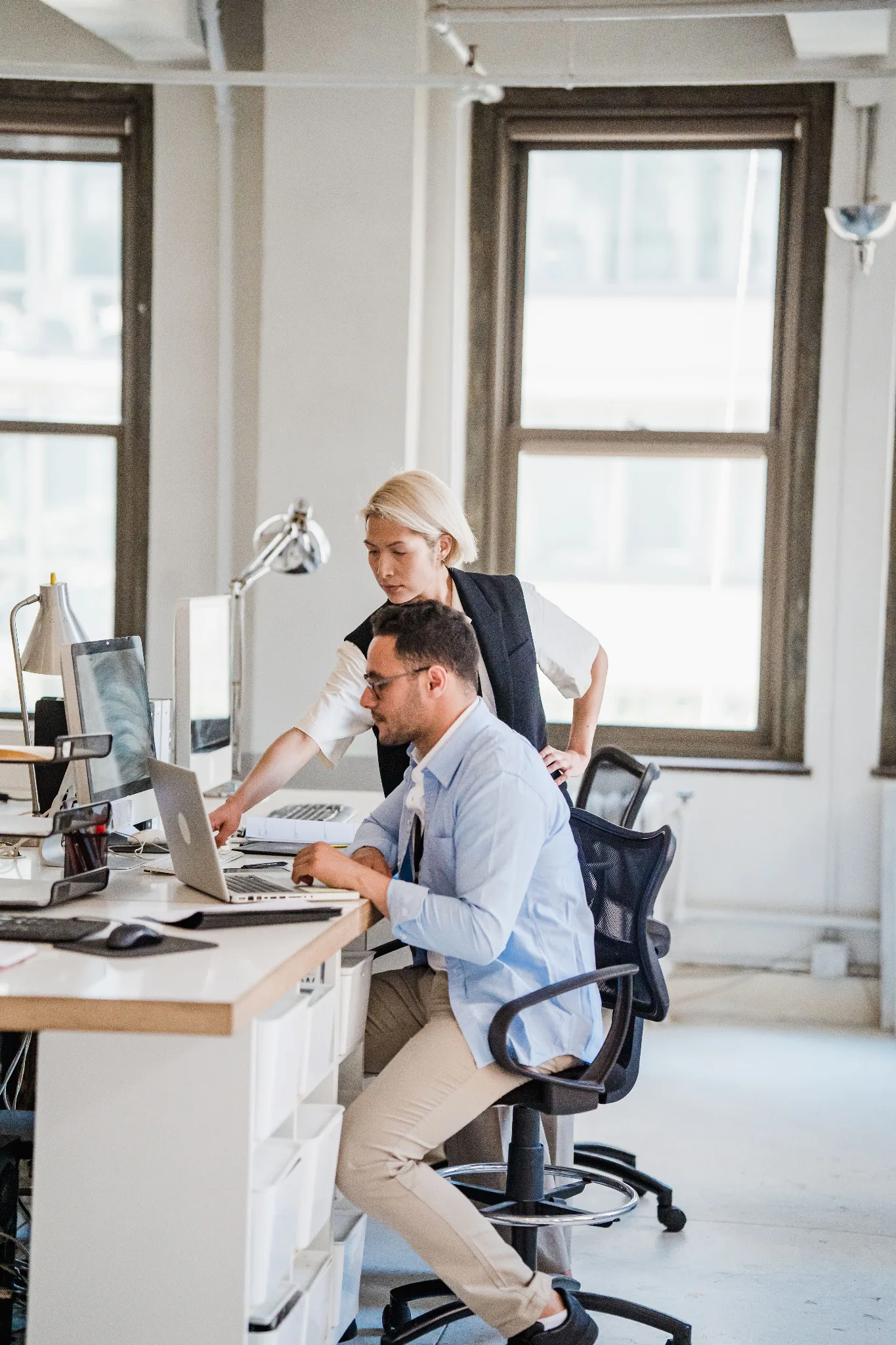 Two coworkers reviewing a laptop at an office desk